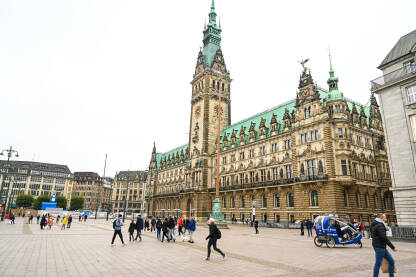 Hamburg, Njemačka: Ljudi šetaju centrom grada. Grupa ljudi i turista u šetnji glavnim trgom u Hamburgu. Zgrada gradske vijećnice.