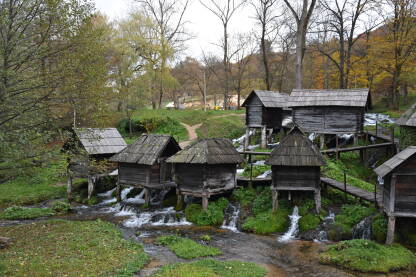Stari mlinovi za žito na Plivskom jezeru u prirodnom krajoliku sa zelenilom i vodom slikanu u kasnu jesen.
