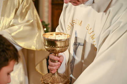 Svećenik daje sakramentalni kruh vjerniku tokom mise. Katolički svećenik daje pričesni kruh u katedrali. Hostija.
