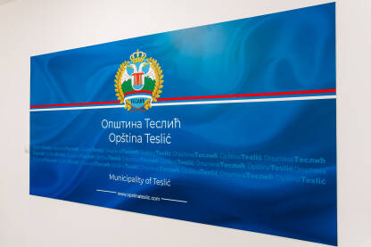 Grb Opštine Teslić na plavoj pozadini sa latiničnim,ćiriličnim i engleskim natpisom Opština Teslić.