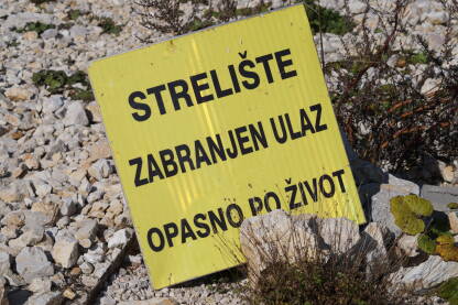 Žuta tabla upozorenja na ulazu u prostor strelišta.