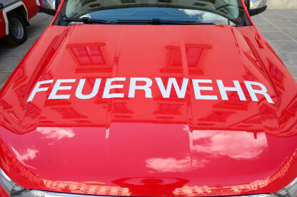 Crveno vatrogasno vozilo u Austriji. Znak vatrogasci na autu. Natpis: Feuerwehr.