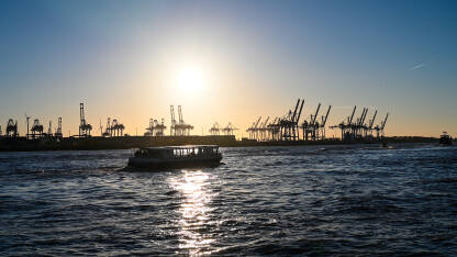 Dizalice u luci na zalasku sunca. Hamburg, Njemačka. Turistički brod na rijeci. Brodska luka.