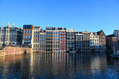 Amsterdam, Holandija: Poznate kuće u gradu Amsterdamu. Tipične holandske kuće sa šarenim fasadama. Kuće uz riječni kanal u centru grada. Historijske građevine.