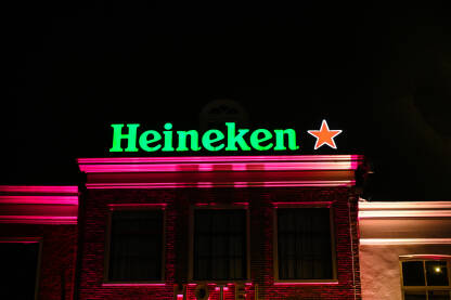 Heineken logo na zgradi. Heineken logo na zgradi. Osvijetljena Heineken reklama noću. Heineken simbol.