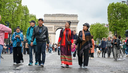Pariz, Francuska: Turisti šetaju čuvenom avenijom Champs-Élysées u Parizu, s Trijumfalnom kapijom u pozadini. Ljudi šetaju ulicom u blizini poznatih znamenitosti.