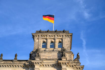 Njemačka zastava na Bundestagu u Berlinu. Zgrada njemačkog parlamenta. Nacionalne zastave vijore na jarbolu u Njemačkoj.