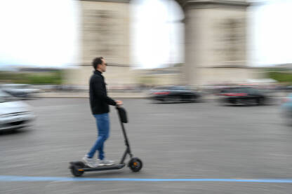 Muškarac vozi električni romobil na ulici. e-skuter. Mutna fotografija čovjeka koji vozi romobil u Parizu, Francuska.
​