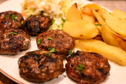 Mljeveno meso s krumpirom i salatom na bijelom tanjuru u restoranu. Hrana. Večera poslužena u restoranu.