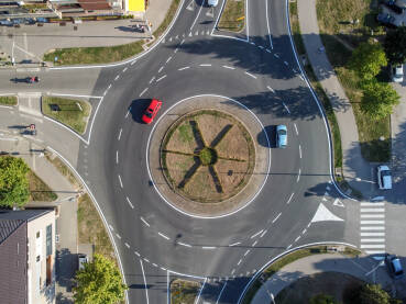 Kružni tok u gradu, snimak dronom. Automobili se kreću cestom unutar kružnog toka. Saobraćaj na kružnom toku, pogled odozgo.