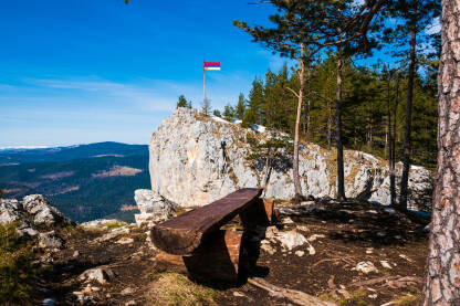 Drvena klupica i pogled na zastavu Republike Srpske na vrhu Crvene stijene, na planini Romaniji