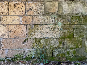 Stari oronuli zid napravljen od betonskih blokova. Zid unutar ruševine, prekriven prljavštinom.