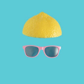 Minimalistički ljetni koncept - polovica limuna i sunčane naočale na svijetloj plavoj podlozi. Ljeto, ljetna zabava, odmor, čovjek.