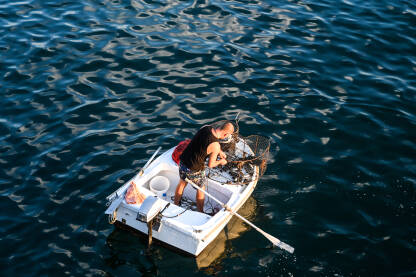 Ribar pregledava ulov iz mora. Ribolovac u čamcu pregledava vršu. Ribolov.