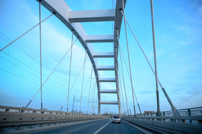 Novi Sad: Most sa lukovima iznad rijeke. Vožnja preko mosta. Veliki bijeli most preko rijeke Dunav.