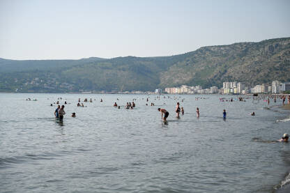 Shëngjin, Albanija. Ljudi plivaju u moru i sunčaju se na plaži. Turisti na ljetnom godišnjem odmori. Popularna turistička destinacija na Jadranskom moru u Albaniji.