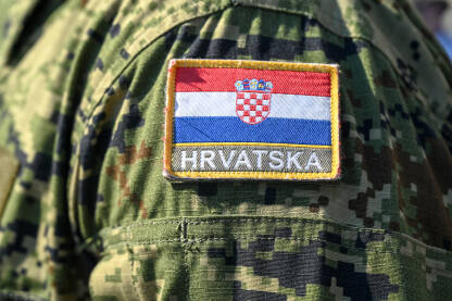 Oružane snage Republike Hrvatske tokom službene ceremonije. Hrvatska zastava na maskirnoj uniformi. Grb na ramenu vojnika.