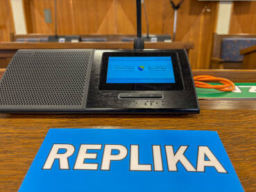 Sjednica u skupštini. Natpis REPLIKApored poslaničkog mikrofona.