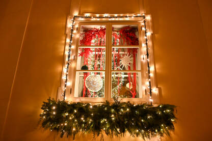 Lijepo ukrašen prozor za Božićne i Novogodišnje praznike. Svjetleći ukrasi na kući. Dom ukrašen svjetlima.