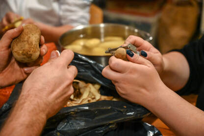 Muškarac i žena gule krompir noževima. Guljenje krompira. Priprema večere.