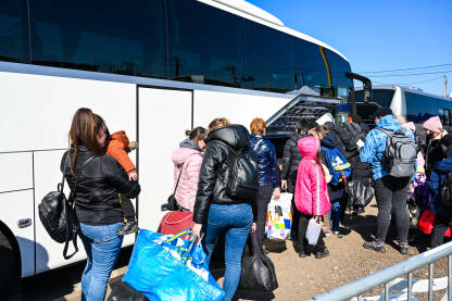 Grupa izbjeglica iz Ukrajine ulazi u autobus. Izbjeglice iz Ukrajine bježe od rata. Ukrajinske izbjeglice prelaze granicu. Ukrajinci bježe od rata.