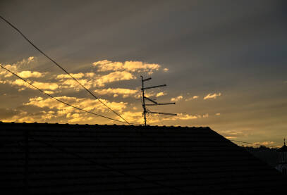TV antena na krovu kuće tokom zalaska sunca.