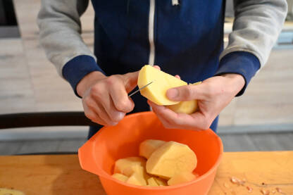 Čovjek nožem guli i reže krumpir. Priprema ručka kod kuće.