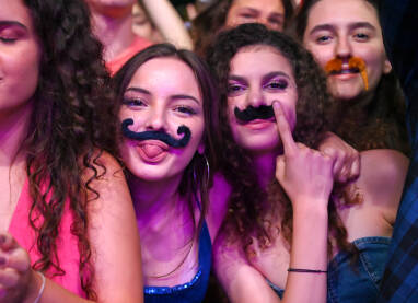 Djevojke se zabavljaju na koncertu. Dvije mlade žene sa lažnim brkovima na muzičkom festivalu. Mladi se zabavljaju.