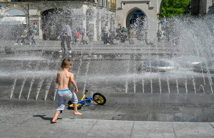 Dječak se osvježava na fontani. Dječak se osvježava vodom vrelog ljetnog dana.