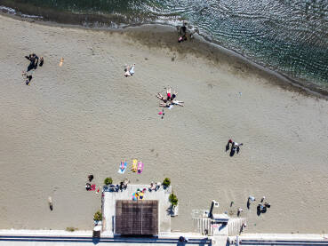Grupa ljudi na plaži uz more. Grupa ljudi na plaži uz more. Ljudi se sunčaju na plaži, snimak dronom.