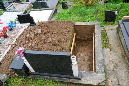 Svježe iskopani grob na groblju. Priprema pogreba. Otvoreni grob na groblju. Sahrana.