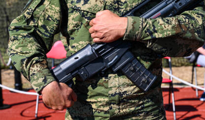 Vojnik u uniformi drži automatsku pušku.