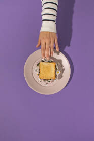 Zenska ruka poseže za tost sendvičem s cvijećem tratinčice.
