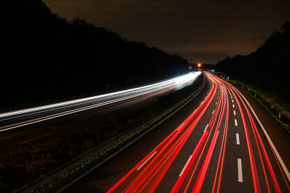 Svjetla automobila na autoputu noću. Snimak vozila u pokretu noći. Duga ekspozicija bijelih i crvenih svjetala autua na putu. Transport.