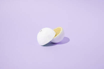 Prepolovljen limun obojen u bijelu boju na ljubičastoj pozadini.