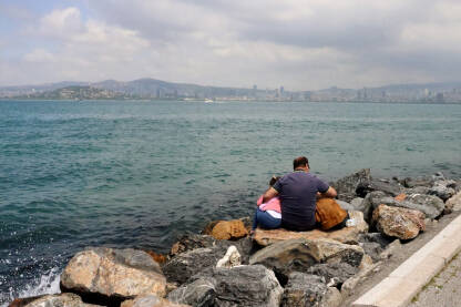 Otac sa djecom u zagrljaju na moru