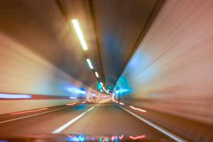 Zamućena fotografija asfaltne ceste u tunelu. Vožnja kroz osvjetljeni tunel. Pogled vozača cestu u tunelu.