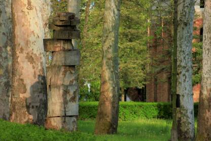Drvena skulptura u parku. Drveće i arhitektura.
