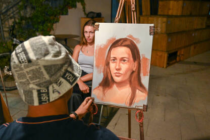 Umjetnik slika portret djevojke na ulici. Ulična umjetnost.