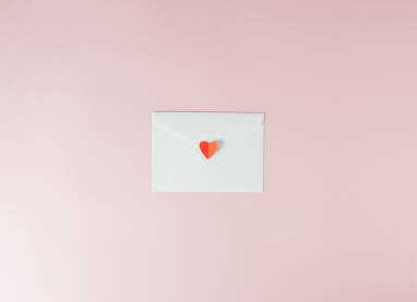 Bijela koverta i crveno papirno srce.