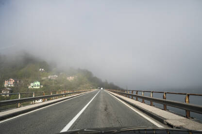 Magla na putu. Vožnja na autoputu po maglovitom vremenu. Teški uslovi vožnje. Pogled na cestu kroz vjetrobransko staklo automobila. Pogled vozača.