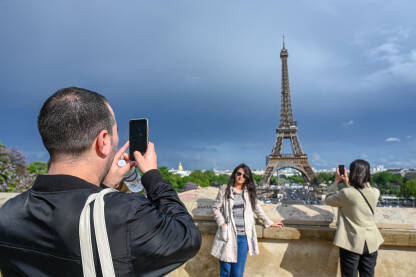 Pariz, Francuska: Turisti se fotografišu ispred Ajfelovog tornja. Popularna turistička destinacija.