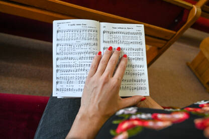 Djevojka se moli u crkvi. Žena drži knjigu tokom molitve. Vjernici se mole.