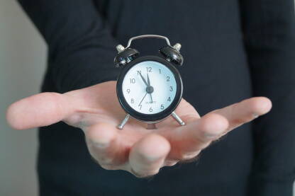 Mali sat na dlanu koji pokazuje 11:55 sati.