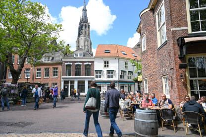 Delft, Nizozemska. Ljudi šetaju gradom. Zgrade, ulice i trgovi.