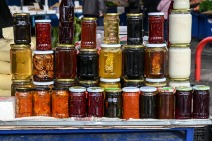 Domaći proizvodi na prodaju na pijaci. Staklenke na štandu na tržnici. Med, pekmez, sać, marmelada i konzervirano voće i povrće na pijaci.
