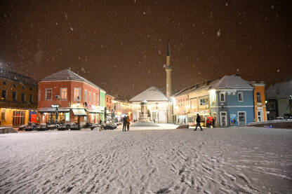 Tuzla, Bosna i Hercegovina. Okićen grad noću. Novogodišnji ukrasi. Glavni gradski trg zimi dok pada snijeg.