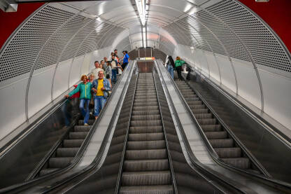 Ljudi na pokretnim stepenicama na stanici metroa. Putnici na pokretnim stepenicama u metrou.