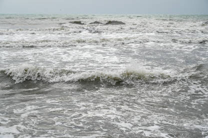 Mutna morska voda nakon kiše. Olujno nevrijeme na obali. Valovi mora s pješčanom sivom i smeđom bojom.