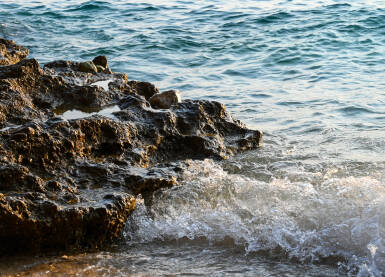 Valovi na stjenovitoj plaži na moru. Kamena morska obala.